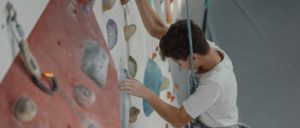 Young boy steadily making way up an indoor climbing wall